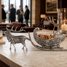 Decorative silver reindeer and sleigh with nuts on a table in a blurred indoor setting