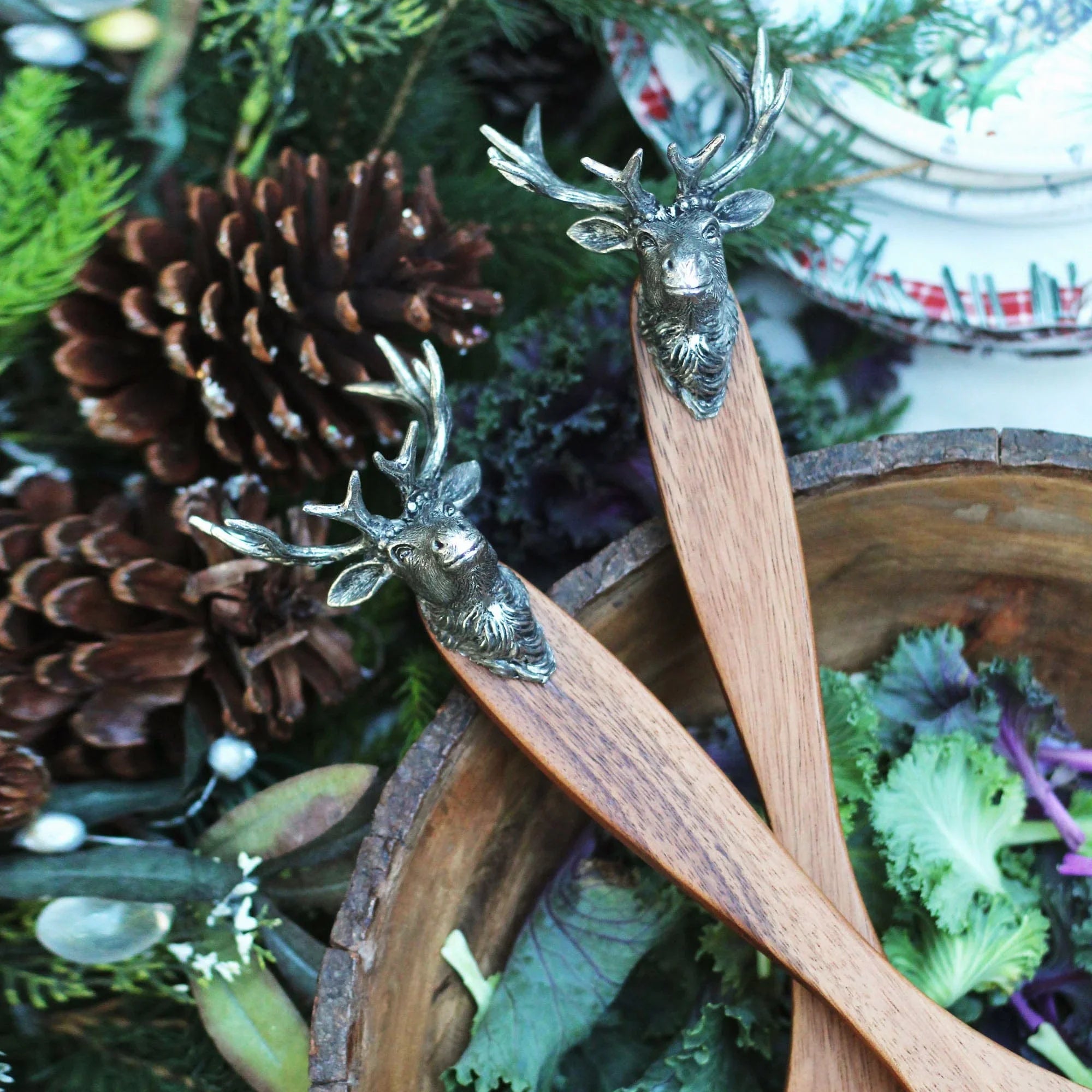 Wooden utensils with elk head handles on a festive background with pine cones and greenery - Your Western Decor
