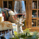 Elk head stem wine glass with red wine on a decorative stand in a cozy indoor setting