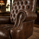 A close-up of a dark brown distressed leather recliner office chair with tufted button detailing, rolled arms, and brass nailhead trim, shown in a warm, rustic room setting.