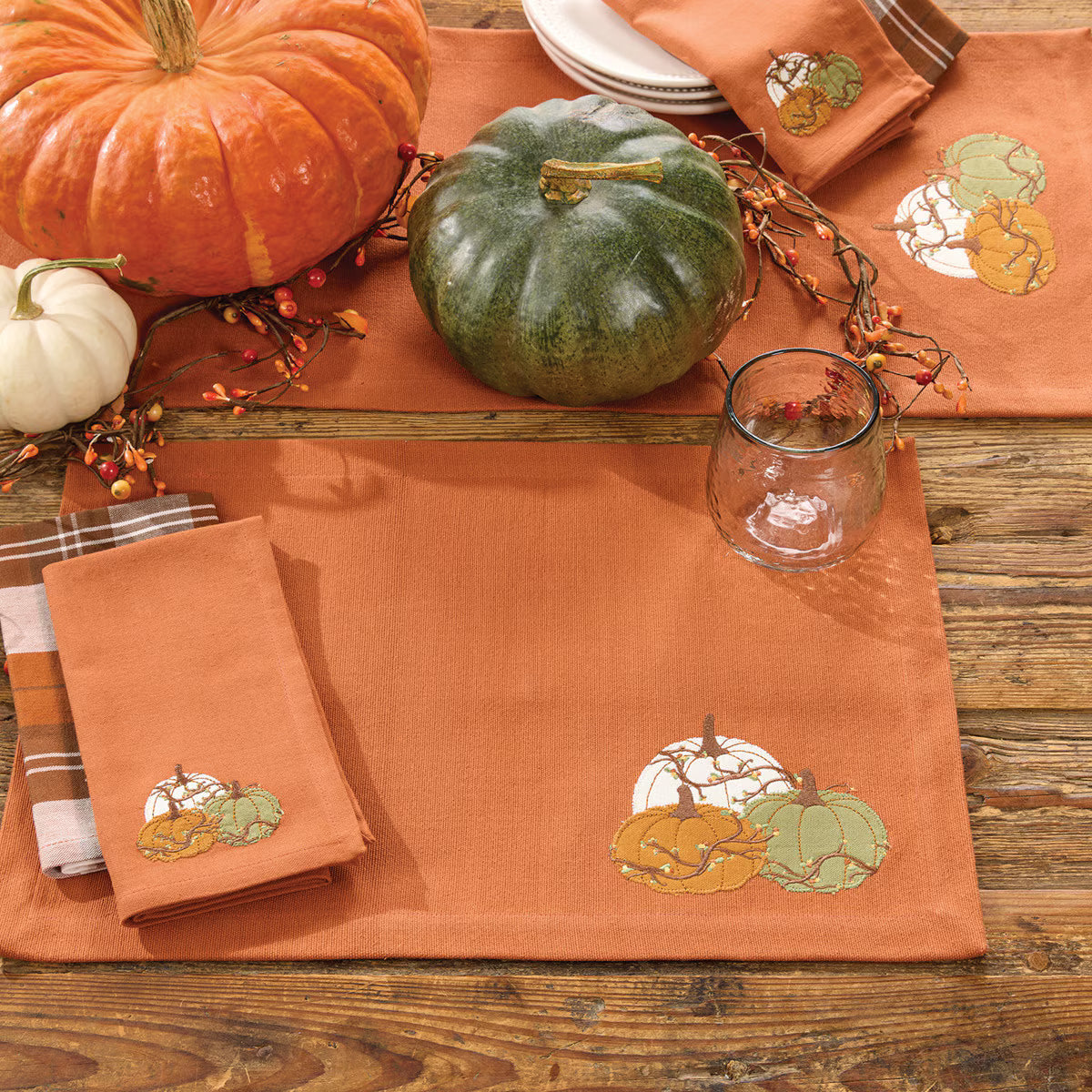 Table setting with pumpkins, placemats, and napkins featuring autumn designs on a wooden table - Your Western Decor