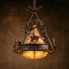 A rustic western-themed metal chandelier pendant light with a conical shade featuring a cutout of a indian riding a horse, and a glowing warm glass globe shade below, suspended by ornate dark metal chains against a textured brown background.