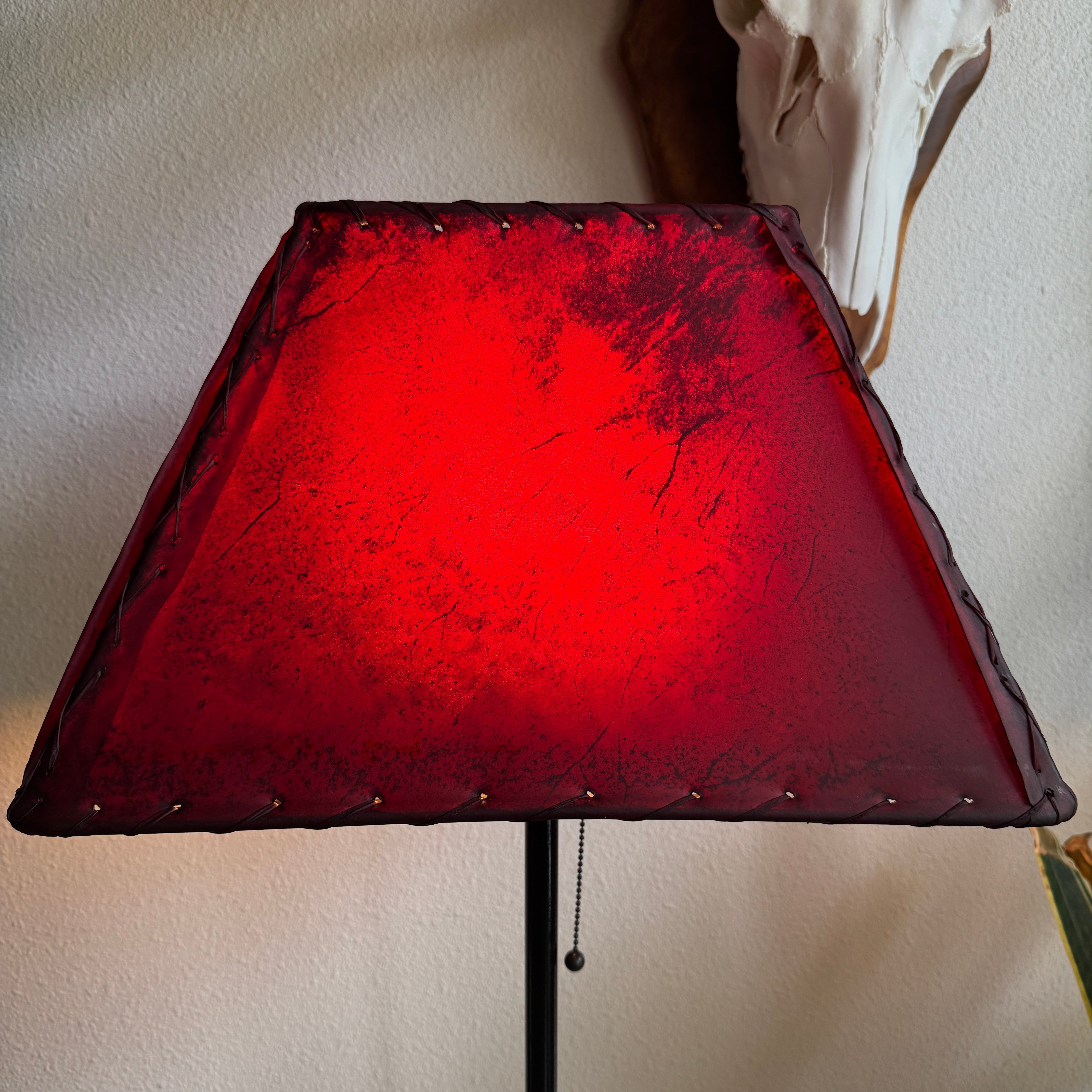 Rectangle red rawhide lamp shade with the light on 