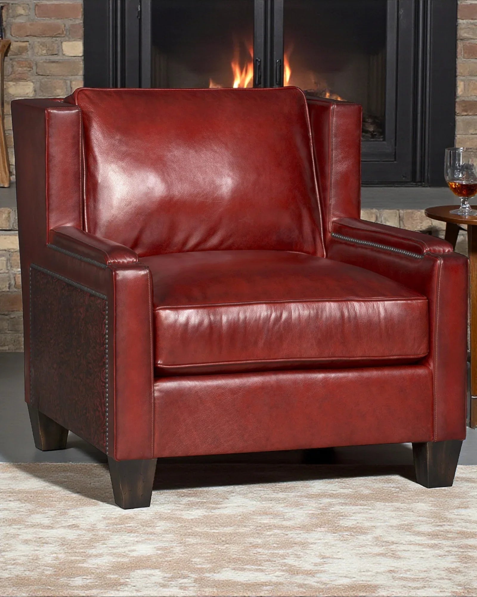Red leather armchair in front of a fireplace with a glass of wine on a table Your Westenr Decor