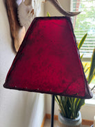 Red rawhide lamp shade in natural lighting, light off 