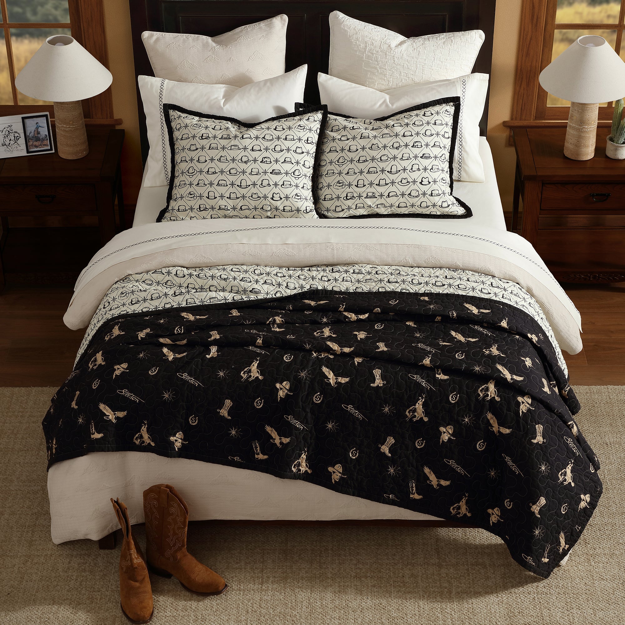 Bed with black and white western patterned quilt and pillows in a bedroom setting.