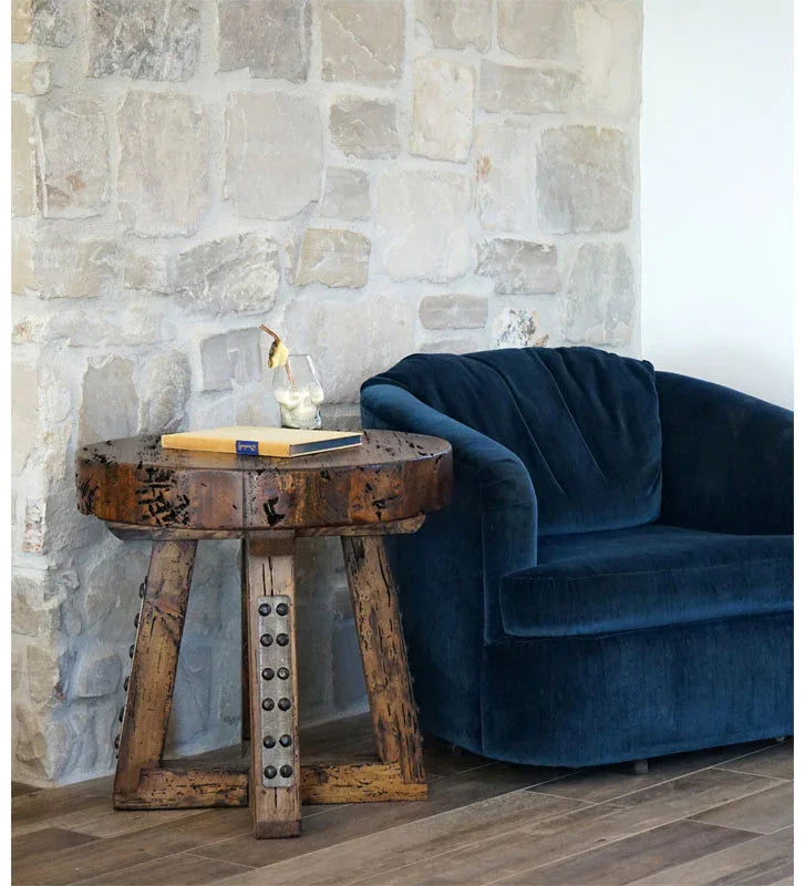 Blue velvet sofa next to a wooden side table against a stone wall - Your Western Decor