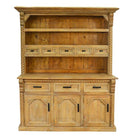 A rustic pine hutch cabinet with a warm yellow-tan finish, featuring three open shelves, five small drawer fronts with dark metal pulls, and three lower cabinet doors with carved panel details and black handles.