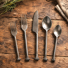 Forged Iron Flatware Set displayed on reclaimed rustic wood tabletop.