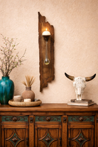 Wooden sideboard with decorative items including a wall-mounted candle holder and a bull skull on a beige wall - Your Western Decor