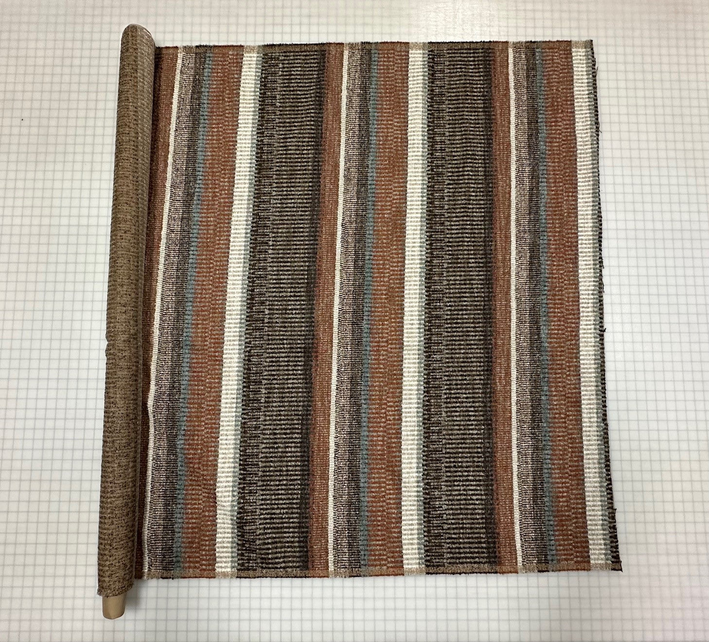 Striped fabric on the roll with brown, beige, and white colors on a grid background