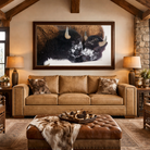 Snow-Kissed Buffalo framed canvas art displayed above a tan leather sofa in a luxury western lodge living room with high wood beam ceilings and rustic décor