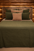 Bed with green and brown bedding against a wooden headboard - Your Western Decor