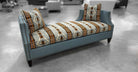 A blue upholstered chaise lounge with a patterned seat cushion and matching back cushions, shown in a modern interior setting.