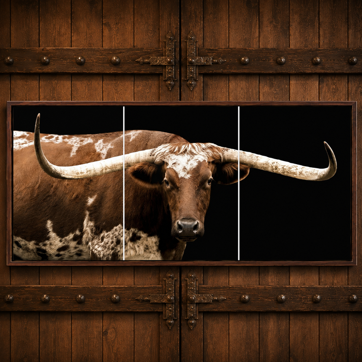 A three-panel canvas wall art print depicting a brown and white spotted longhorn steer against a black background, mounted on a rustic dark brown wooden door.