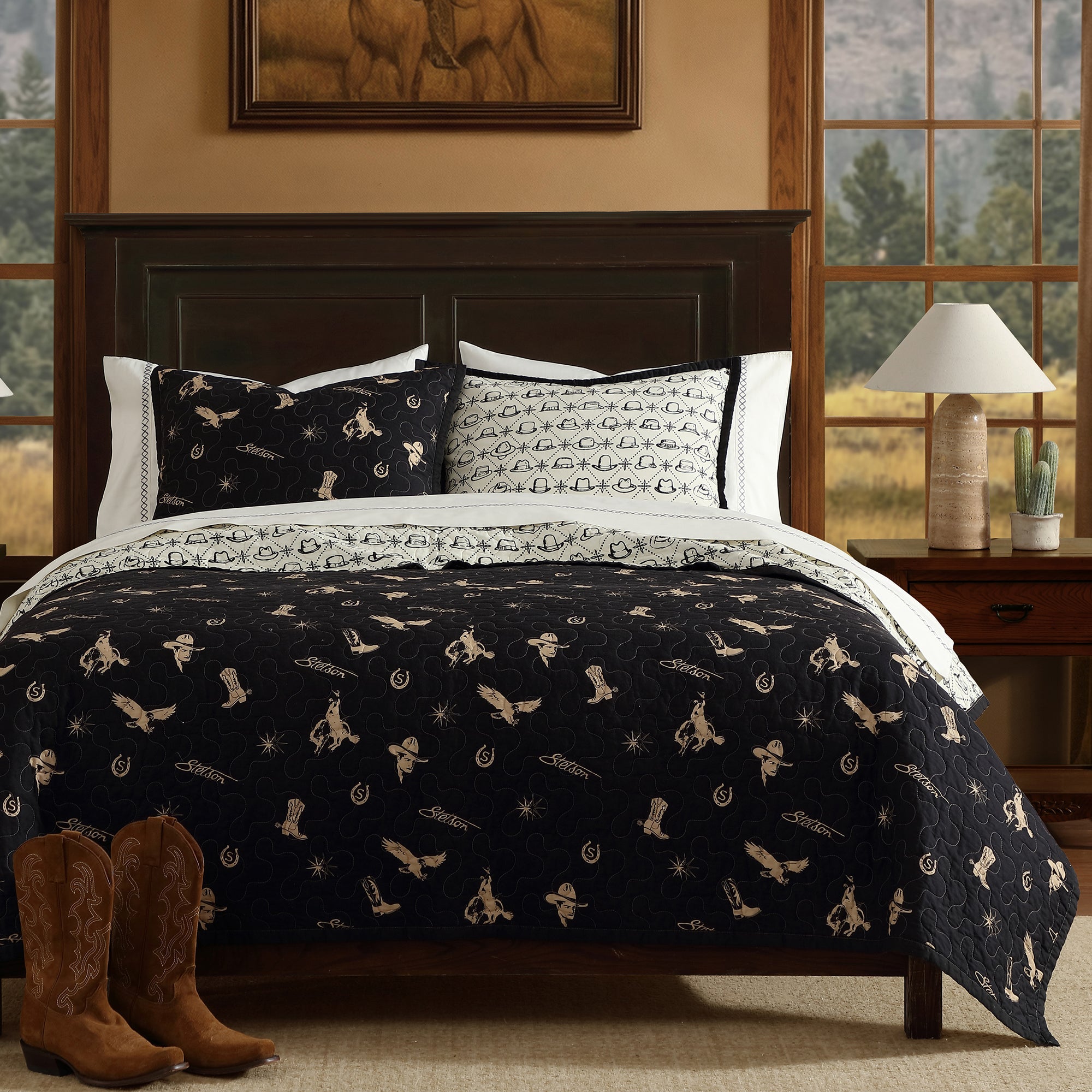 Bedroom with a bed featuring a black and white western patterned quilt, cowboy boots, and a lamp.