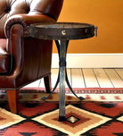 Small round metal table with decorative legs next to a brown leather chair on a patterned rug. Your Western Decor