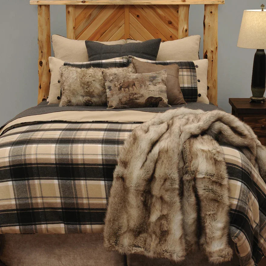 Bed with plaid bedding and fur throw, wooden headboard, and lamp on nightstand - Your Western Decor