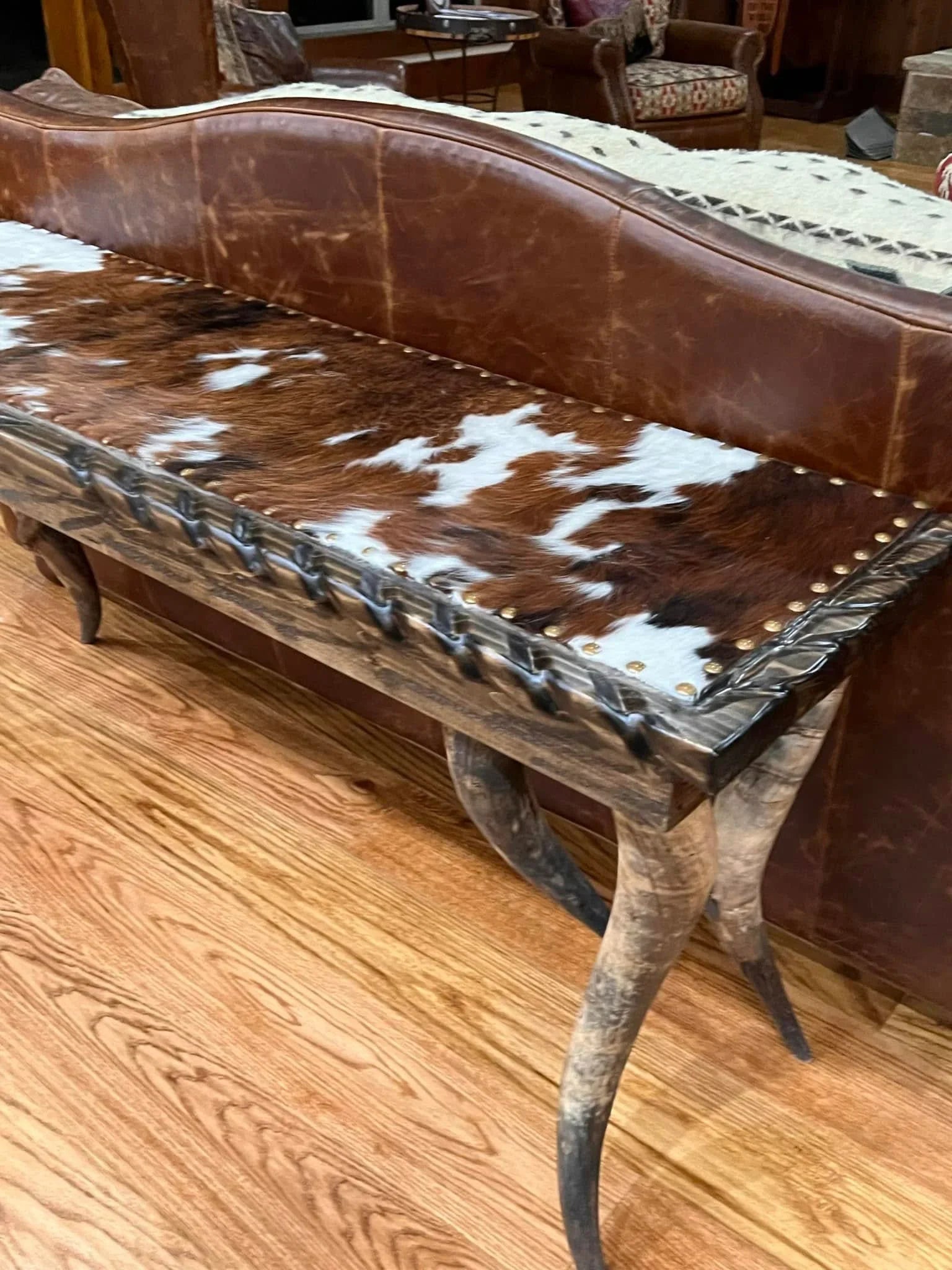 Longhorn Ranch Cowhide Console Table with genuine steer horn legs and black-and-white cowhide upholstery in a rustic Western living room