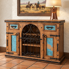 Rustic wooden sideboard cabinet with turquoise patina copper drawer fronts and decorative black metal hardware, shown in a styled interior setting with a lamp and framed artwork on a wall.