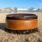 Cowhide and leather round ottoman with fringe and nail trim 