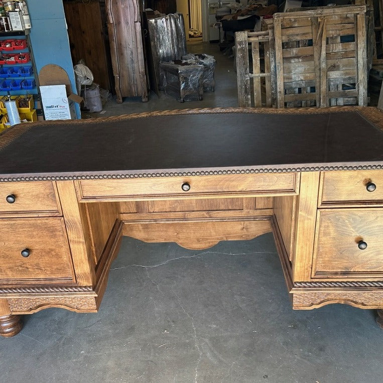 Front view of western executive desk with leather top and nailhead trim 