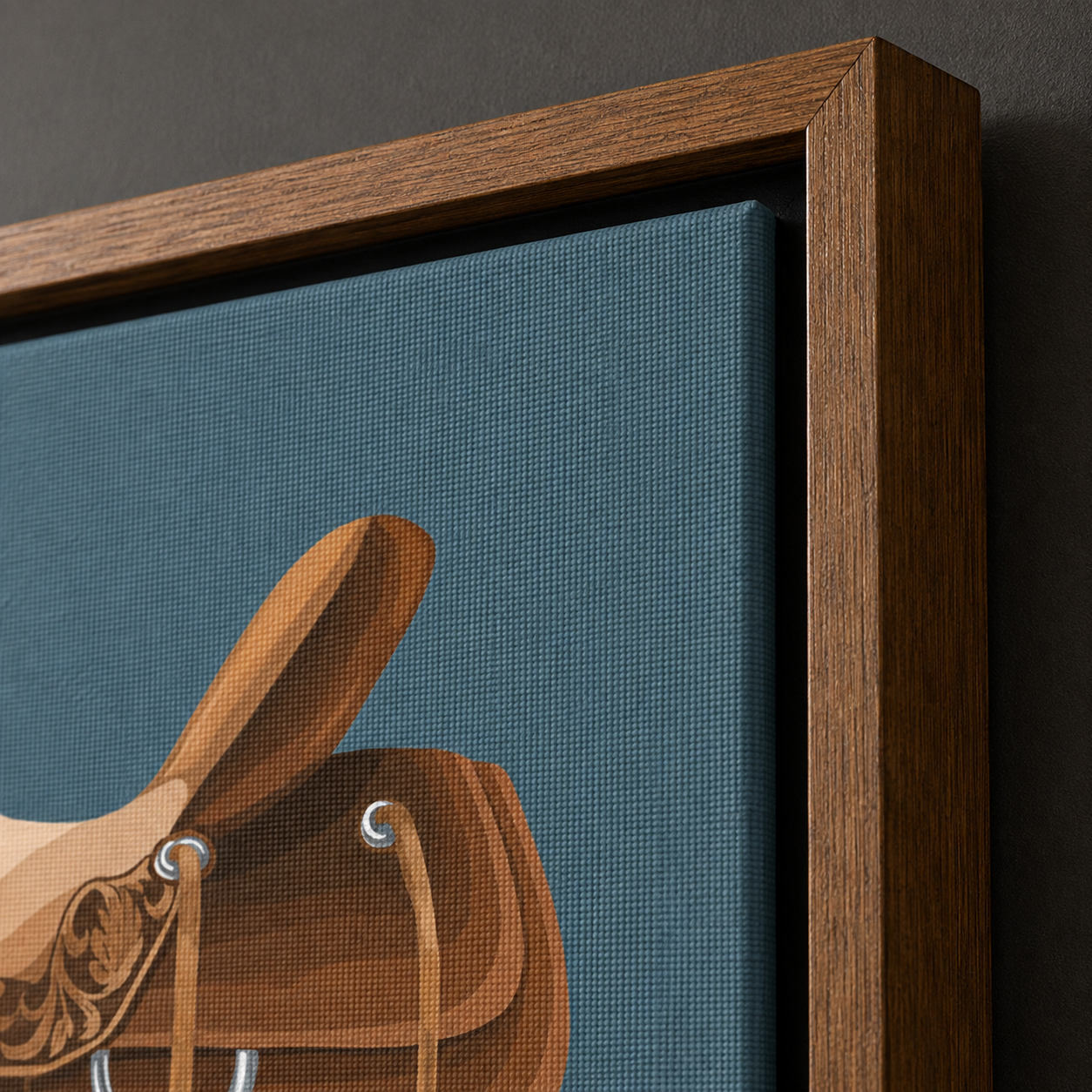 Close-up of a framed wall art print showing a stylized brown leather saddle on a textured dark teal-blue background, with a medium-brown wooden frame against a dark wall.