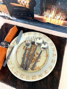 place setting with bull riding western dinner plate, napkin with cowhide napkin ring, cowhide placemat, and hammered copper flatware 
