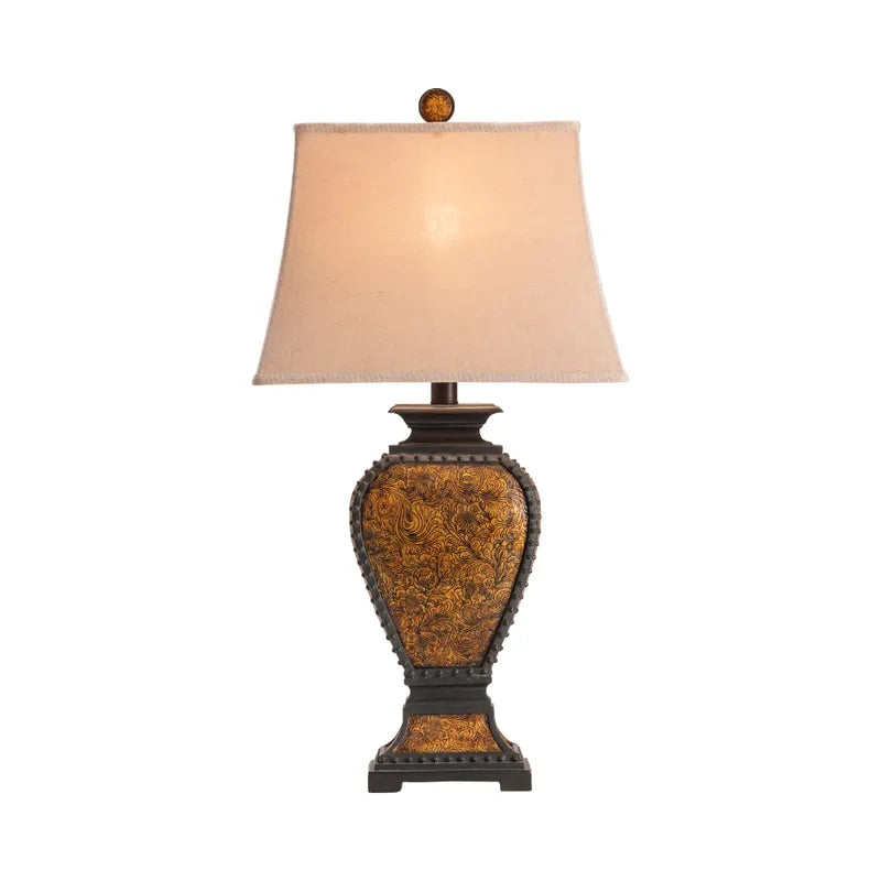 Resin tooled leather look western table lamp with linen shade and light on - Your Western Decor