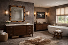 Western wood and cowhide vanity mirror mounted above stone bathroom sink in rustic ranch interior