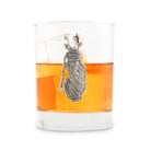 Glass with a silver pendant and orange liquid on a white background