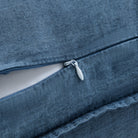 Close-up of a blue denim or canvas fabric item with a zipper opening, showing the texture of the material and a small white pull tab.