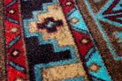 Blue Zircon Southwestern Carpet Detail in geometric patterns of turquoise, red, beige and black over distressed brown background 