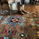 Blue Zircon Southwestern Rug in geometric patterns of turquoise, red, beige and black over distressed brown background 