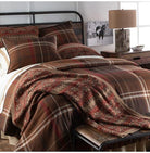 Brown lodge plaid comforter set styled in a luxury rustic resort bedroom with iron and wood bed, rustic lamp, and horse art